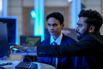 A team of financial analysts in a trading room monitors real-time market data. The lead analyst points out a critical trend, guiding the team's investment strategy after hours.