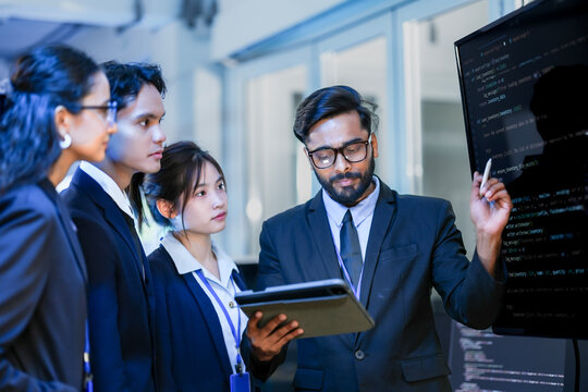 A senior software architect leads a code review session, explaining a complex algorithm to junior developers. He uses a stylus to highlight specific functions on the main display.
