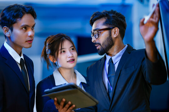 A project manager leads a strategy session with his development team in a corporate war room. He outlines the next sprint's objectives based on the current data analytics.