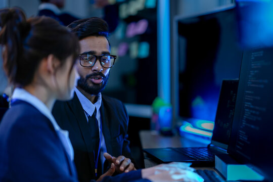 An agile development team participates in a sprint retrospective meeting. A female developer contemplates the user stories on the kanban board visible in the background.