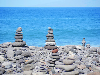 Stone Cairns on Rocky Beach with Blue Sea in Background