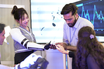 A team of young inventors works on a futuristic robot arm. A man helps a woman try on the high-tech arm, representing the future of technology and helping people.