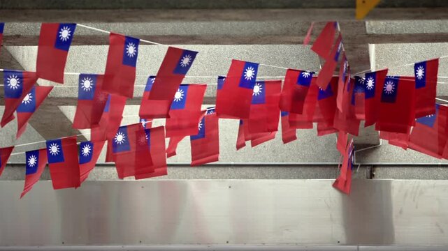 Slow motion of Taiwan flags fluttering in a public space, symbolizing unity and patriotism in an urban environment with concrete structures.