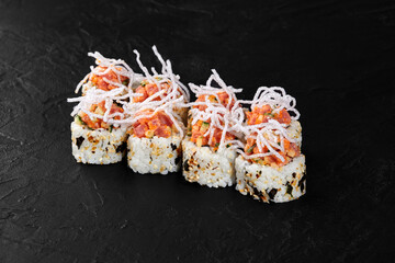 Spicy tuna uramaki sushi rolls with crispy onions on black background