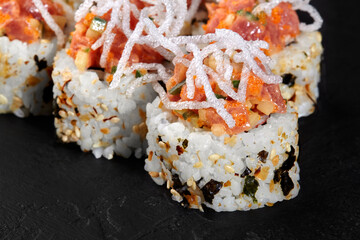 Spicy tuna uramaki sushi rolls with crispy onions on black background