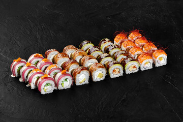 Delicious sushi rolls set displayed on black background