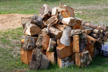 Chopped firewood lies on green grass. Horizontal shot.