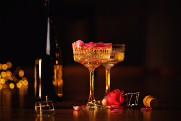 A bottle of champagne with two crystal glasses, rose petals, and warm candlelight, evoking an...
