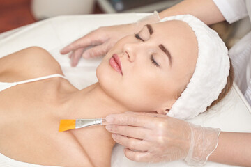 Female adult caucasian receiving facial mask treatment at spa with relaxed expression and spa headband.