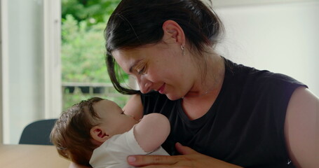 Mother and baby enjoying a loving moment, with the baby comfortably nestled in her arms,...
