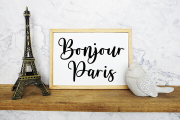 Bonjour Paris text written on whiteboard with Eiffel Tower Souvenir and bird statue on wooden shelf © may1985