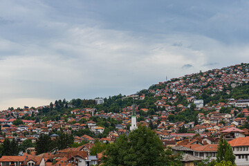 Fototapeta premium top aerial view of sarajevo city with huge areas and neighbourhoods of houses in cloudy day with mountains around bosnia