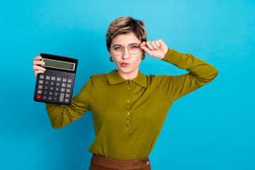 Portrait of a confident young businesswoman in a stylish outfit posing with a large calculator...