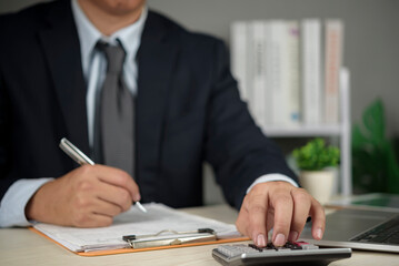 Financial planning, Professional businessman calculates numbers on calculator while working with laptop and papers, analyzing budget, audit, and accounting data.