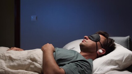 The man puts a sleep mask on his face and plugs his ears with earplugs - Powered by Adobe