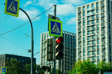 A pedestrian crossing with a road sign and a traffic light showing a red signal. In the background...