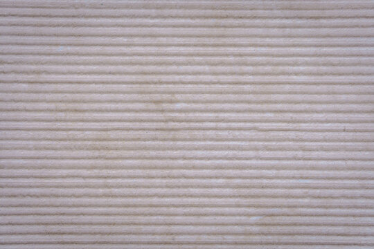 A textured stone surface with evenly spaced horizontal ridges forms a rhythmic pattern. The material emphasizes durability and the natural expressiveness of texture.