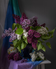 A stunning arrangement of beautiful lilacs displayed in a vintage jug surrounded by books and fabric