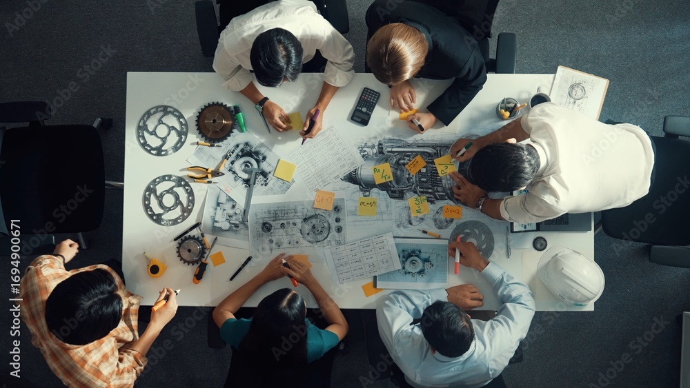 Poster top view of smart engineer team in casual cloth talking about turbine engine structure at table with