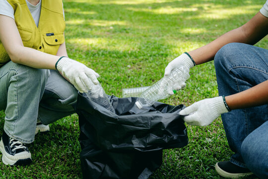 Volunteer hands carefully sort plastic bottles for recycling during community cleanup event promoting environmental sustainability in a green park outdoor setting