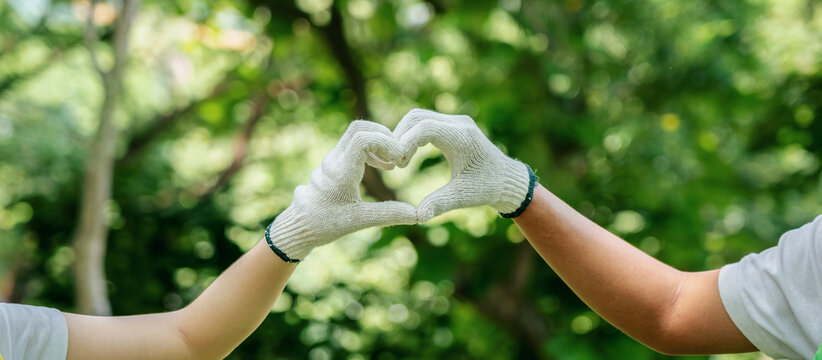 Volunteers working in nature show environmental love with gloved hands forming heart for sustainability recycle efforts