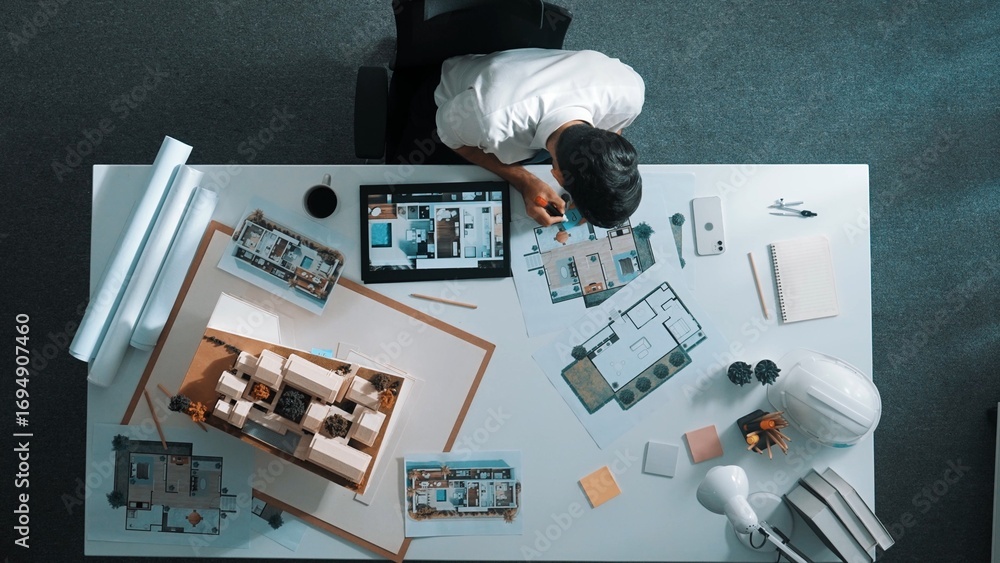 Poster top view of project manager writing house idea on sticky notes while looking plan at tablet. aerial 