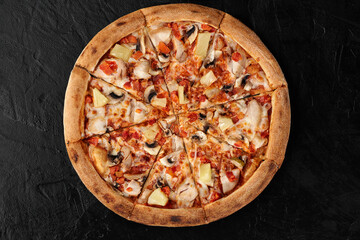 Delicious hawaiian pizza with chicken, pineapple, and mushrooms resting on black background
