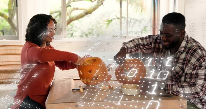 Couple lifting pumpkin lids and scooping pulp at wooden table for DIY seasonal decoration