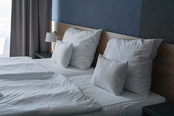 Two neatly made hotel beds with white linens and folded towels prepared for a family couple,...