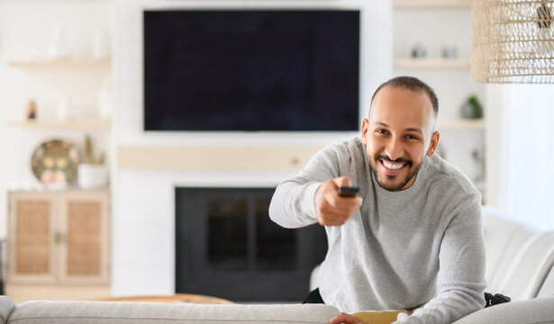 young islamic arab man relaxing on sofa at home watching tv