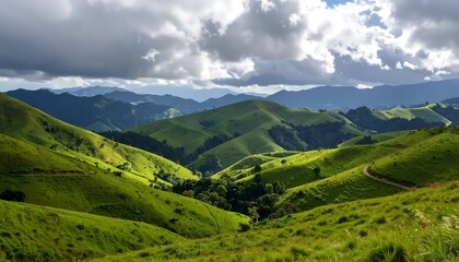 Obraz premium Rolling green hills under a dramatic, cloudy sky. Light and shadow play across the landscape. 