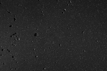 Black industrial metal wall surface with scattered white dot spatter