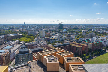 Obraz premium Panoramic view of Berlin with many buildings and green spaces. The white roof of the Tempodrom is visible.