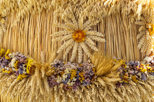 Traditional harvest festival decoration made of cereal ears and dried flowers arranged in ornamental pattern.