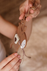 Woman holding wooden Christmas reindeer decoration with string. Holiday craft preparation and festive home decor concept.