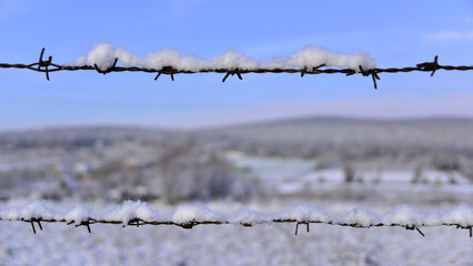 Barbed wire fence covered in snow.