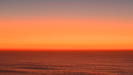 Obraz premium Reddish-orange sunset over the Atlantic Ocean.