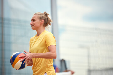 Female volleyball player holding a ball ready for practice outdoors under sunlight