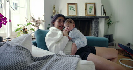 Mother cuddling baby close, kissing baby's head as they both enjoy a peaceful and affectionate...