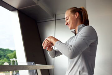 Active woman checking smartwatch on balcony with nature in the background