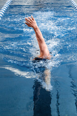 Person swimming with a strong backstroke in an indoor pool setting
