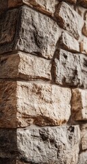 Close-up view of a stone wall, featuring various shades of beige and gray.  Textured, irregular blocks