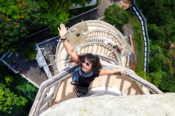 Woman on top of tower, waving happily, scenic view, sunny day. Ambuluwa. Sri Lanka