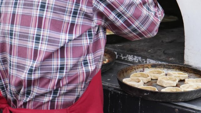 The cook takes out the cooked perepechi pies, a national Udmurt dish, from the oven at the festival of cuisines of small peoples of Russia.