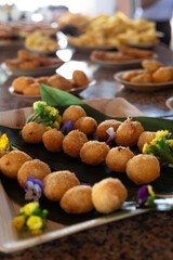 Crispy golden fried cheese balls served on a banana leaf and decorated with edible flowers, perfect for a party or appetizer table.