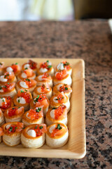 Mini vol-au-vents filled with cream and red caviar, garnished with herbs, arranged on a wooden tray for a festive gathering.