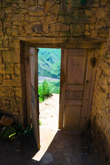 Old open wooden door with view of mountains. Caucasus
