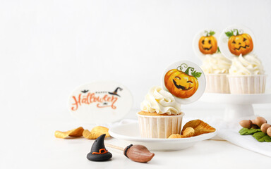 Halloween cupcakes with pumpkin toppers and festive sugar decorations on white background