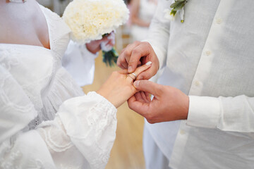 Groom places a wedding ring on bride’s finger during ceremony, symbol of love and eternal bond.