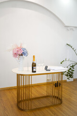 Decorative wedding table with champagne, glasses, rings and bouquet ready for ceremony.